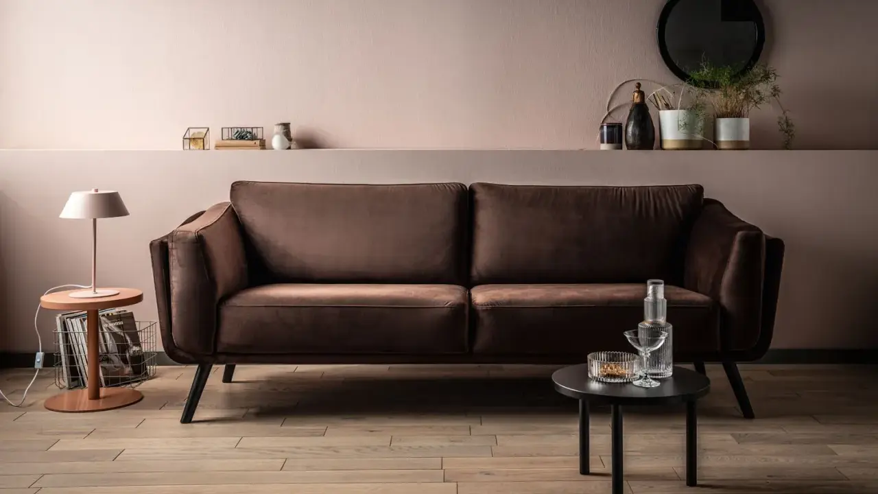 Elegancka brązowa kanapa w salonie. Delikatny różowy kolor ścian i subtelne dodatki pokazują, jaki kolor pasuje do brązu, tworząc przytulną atmosferę.