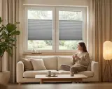 Kobieta pije kawę w salonie w stylu japandi. Jasna sofa, duża roślina i lampa tworzą przytulną atmosferę.