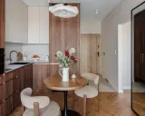 Przytulna jadalnia w stylu mid century z okrągłym stołem, dwoma fotelami i bukietem kwiatów.