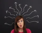 Dziewczyna z wyrazem zaskoczenia na twarzy, z językiem wysuniętym, nad jej głową rysunki strzałek symbolizujące chaos myśli. Jak uspokoić myśli?