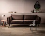 Elegancka brązowa kanapa w salonie. Delikatny różowy kolor ścian i subtelne dodatki pokazują, jaki kolor pasuje do brązu, tworząc przytulną atmosferę.
