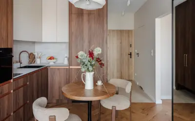 Przytulna jadalnia w stylu mid century z okrągłym stołem, dwoma fotelami i bukietem kwiatów.