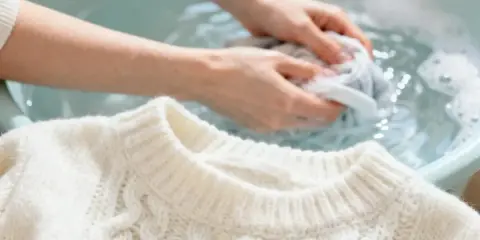 Delikatne pranie wełny w 40 stopniach. Ręce delikatnie ugniatają sweter w wodzie, dbając o jego miękkość.
