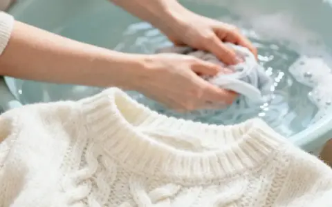 Delikatne pranie wełny w 40 stopniach. Ręce delikatnie ugniatają sweter w wodzie, dbając o jego miękkość.