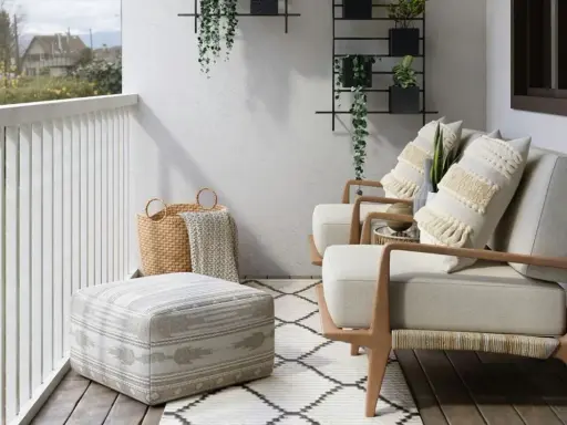 Wąski balkon w bloku inspiracje: przytulne fotele, pufy, kosze i rośliny tworzą oazę spokoju.