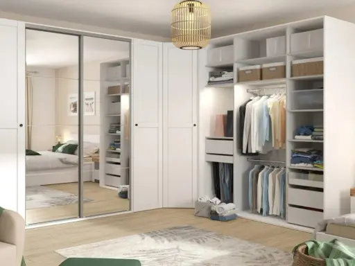 Zorganizowana garderoba w stylu Marie Kondo: białe fronty, lustrzane drzwi, półki z pudełkami i wieszaki z ubraniami.
