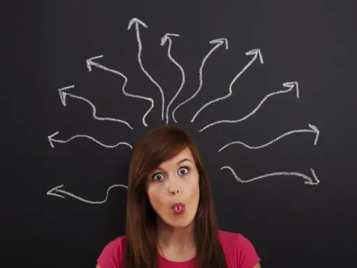 Dziewczyna z wyrazem zaskoczenia na twarzy, z językiem wysuniętym, nad jej głową rysunki strzałek symbolizujące chaos myśli. Jak uspokoić myśli?