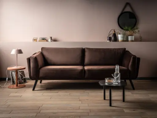 Elegancka brązowa kanapa w salonie. Delikatny różowy kolor ścian i subtelne dodatki pokazują, jaki kolor pasuje do brązu, tworząc przytulną atmosferę.