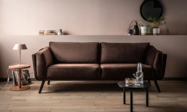 Elegancka brązowa kanapa w salonie. Delikatny różowy kolor ścian i subtelne dodatki pokazują, jaki kolor pasuje do brązu, tworząc przytulną atmosferę.
