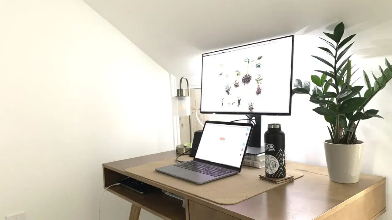 Biurko z laptopem, monitorem i rośliną. Na ekranie komputera widnieje lista marzeń i celów, inspirująca do działania.